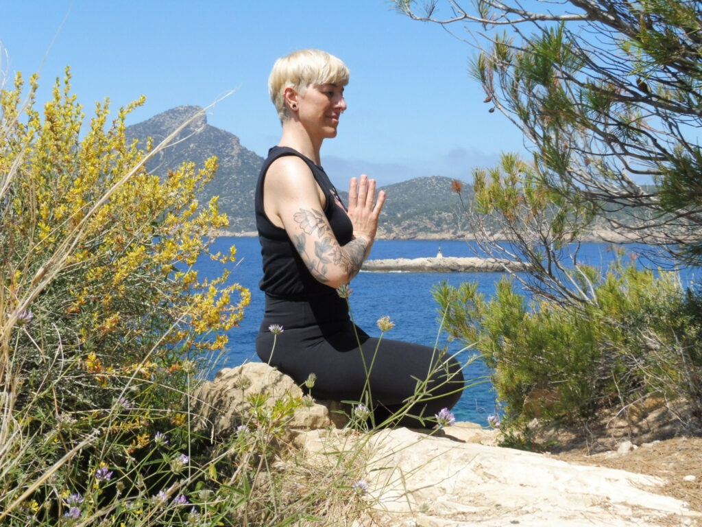 Heike sitzend mit Hände in Gebetshaltung vor dem Herzen als Asana